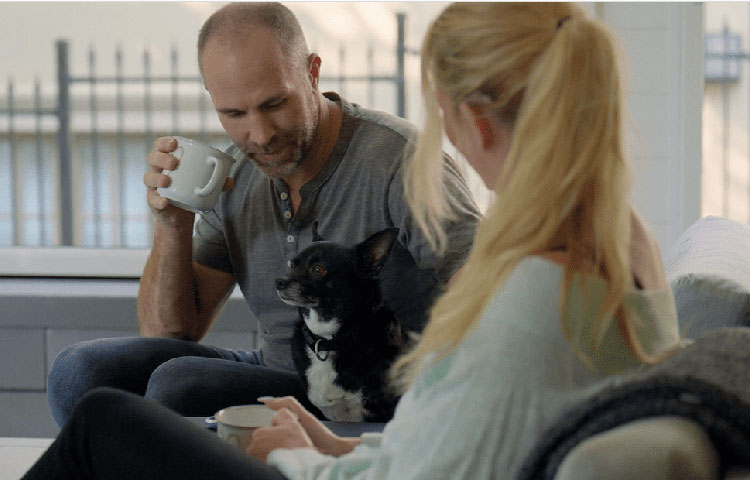 Couple relaxing on couch with small black and white dog